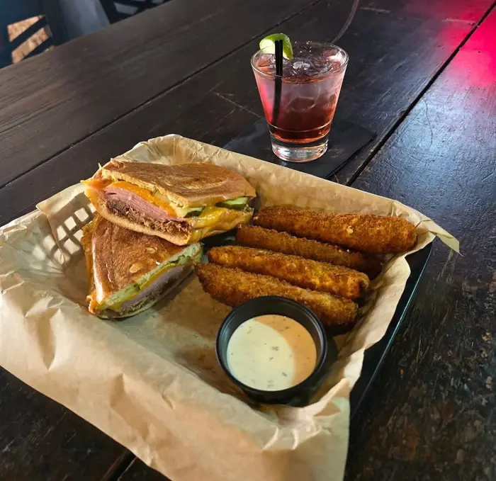 A table at Old Towne Pub set with a reuben and sweet potato fries, fish and chips with slaw, chili cheese fries and smoked trout dip with tortilla chips