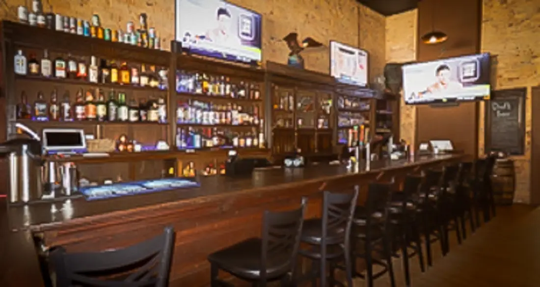 The hand carved wooden bar at Old Towne Pub with its carved detailing and rows of bottles behind