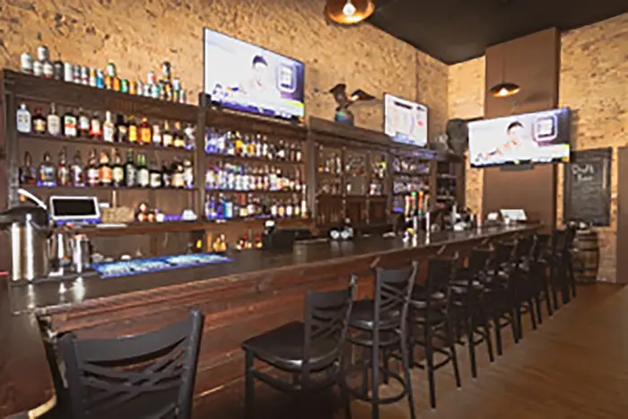 The long wooden bar at Old Towne Pub running the length of the room with stools pulled up to it