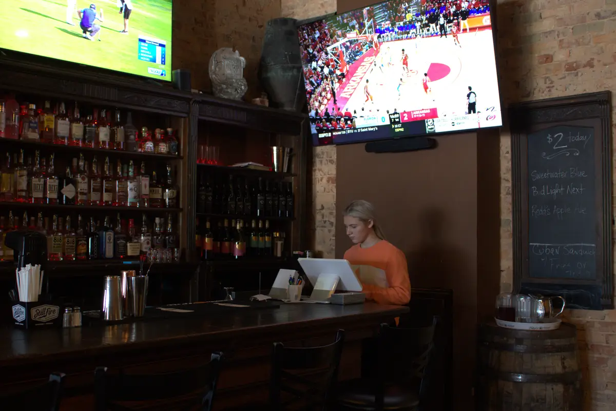 Exposed original brick wall and dark wood shelving inside Old Towne Pub