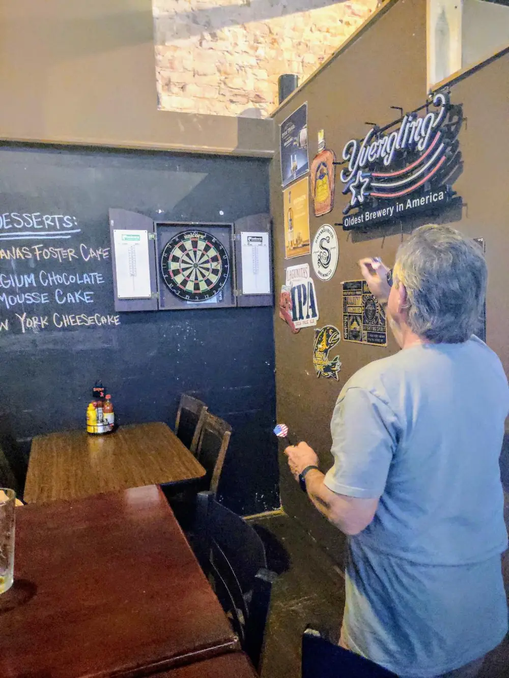 Two people throwing darts at the boards on the back wall of Old Towne Pub